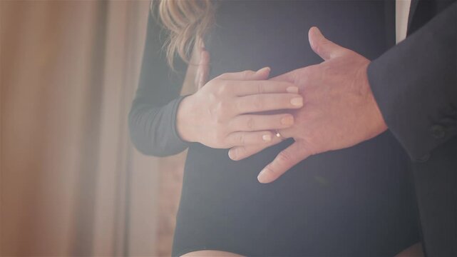Pregnant woman lovingly caressing her belly with husband's hand resting on top, expressing affection and excitement for their baby on the way