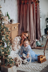 Smiling girl with mom near christmas tree at home