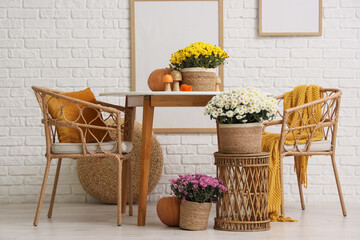 Dining table and chrysanthemum flowers  near white brick wall in room