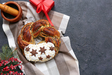 Composition with tasty Christmas pastry wreath, poppy seeds, gift box and decor on dark background