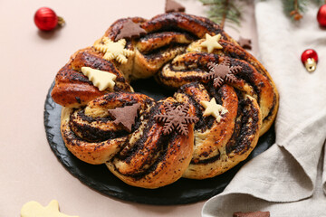 Slate board with tasty Christmas pastry wreath, napkin and decorations on color background