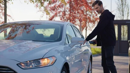 Smiling man opens car-sharing auto using mobile application