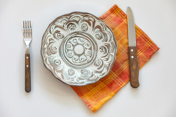 Empty plate isolated on white background with rustic cutlery set next to it