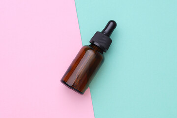 Glass Bottle of Facial Serum on pink blue Background