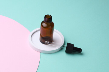 Glass Bottle of Facial Serum with pipette in tray on pink blue Background
