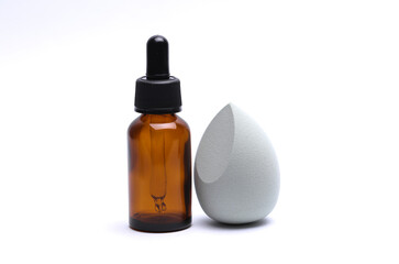 Egg makeup sponge and serum bottle on white background