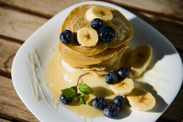 Delicious pancakes with banana slices and blueberries