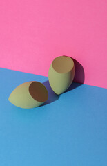 Eggs makeup sponges. Blenders for foundation on pink blue background. Creative layout. Beauty concept