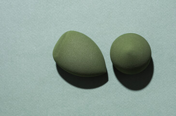Eggs makeup sponges. Blenders for foundation on green background with shadow. Creative layout. Beauty concept