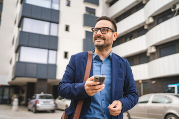 Fototapeta premium businessman stand in front modern business center and use mobile phone