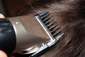 Close-up of hair clippers trimming brown hair in a salon setting