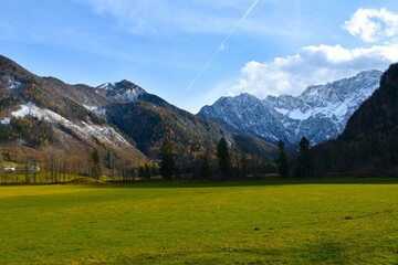 Hills and snow covered mountains in Ravenska Kočna valley and green meadow at Zgornje Jezersko in Gorenjska, Slovenia