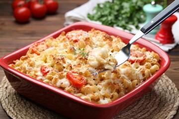 Eating delicious al forno pasta at wooden table, closeup