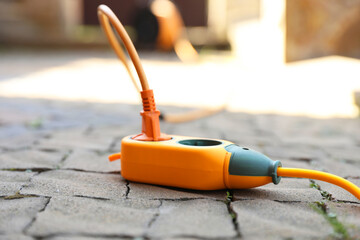 Orange extension cord outdoors on sunny day, closeup