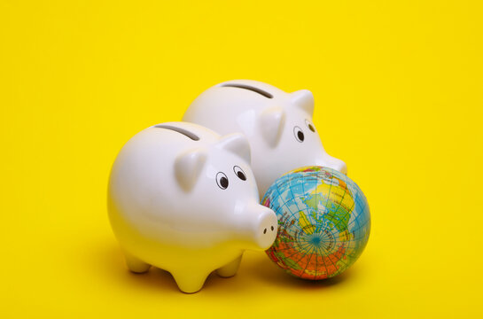 Ceramic white piggy bank with globe on a yellow background. Business concept. Conceptual photo