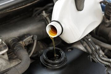 Man pouring motor oil into car engine, closeup