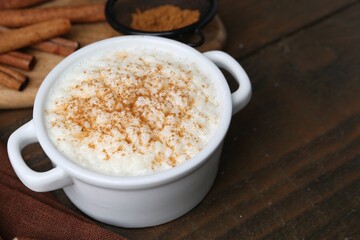 Delicious rice pudding with cinnamon on wooden table, closeup. Space for text