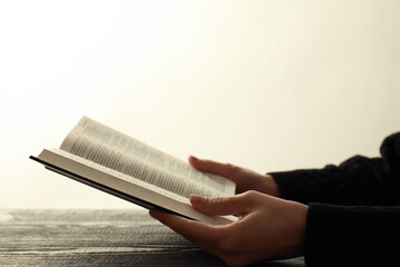 Woman with open Holy Bible in English language at wooden table, closeup