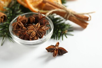 Different spices, dried orange slices and fir tree branches on white table, closeup. Christmas season