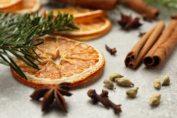 Different spices, dried orange slices and fir tree branches on light grey table, closeup. Christmas season