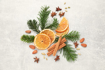 Different spices, dried orange slices and fir tree branches on light grey table, flat lay. Christmas season