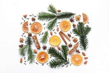 Different spices, dried orange slices and fir tree branches on white table, flat lay. Christmas season