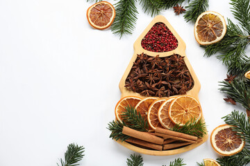 Different spices, dried orange slices and fir tree branches on white table, flat lay with space for text. Christmas season