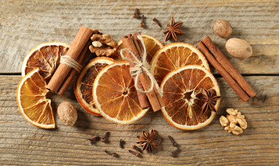 Different spices and dried orange slices on wooden table, flat lay. Christmas season