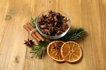 Different spices, dried orange slices and fir tree branches on wooden table. Christmas season