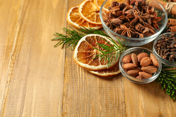 Different spices, dried orange slices and fir tree branches on wooden table, closeup with space for text. Christmas season