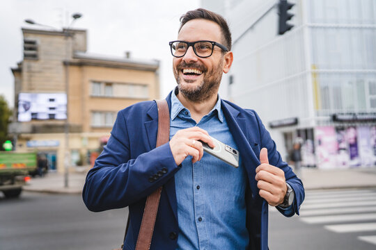handsome businessman put the phone in pocket in front company
