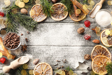 Frame of different aromatic spices and fir tree branches on wooden table, flat lay with space for text. Christmas season