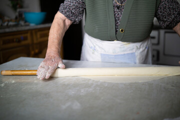 close up of grandmother rolling dough with a rolling pin. Elderly woman rolling out dough with a rolling pin