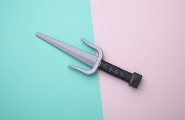 Toy plastic sai weapons on blue pink background
