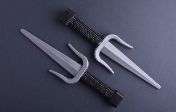 Toy plastic sai weapons on gray background