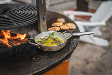 Rustic outdoor cooking setup with rosemary, butter and potatoes