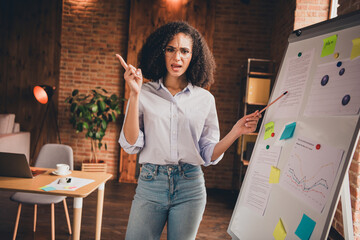 Confident businesswoman presenting in a office setting, using a flip chart to discuss financial statistics.