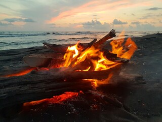 A fire is burning on the seashore, evening clouds in the sky