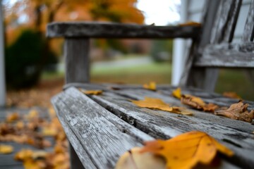A weathered wooden bench decorated with fallen autumn leaves, evoking a sense of peace and nostalgia on a serene porch environment, captured in rich detail.