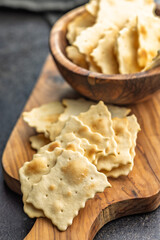 A crispy salted crackers on cutting board on black table.