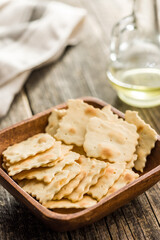 A crispy salted crackers in bowl on wooden table.