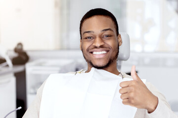 Quality Dental Services. Portrait Of Happy Young Black Guy Sitting In Chair In Stomatological...