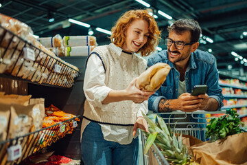 Happy couple choosing bread in supermarket, reading ingredients on smartphone