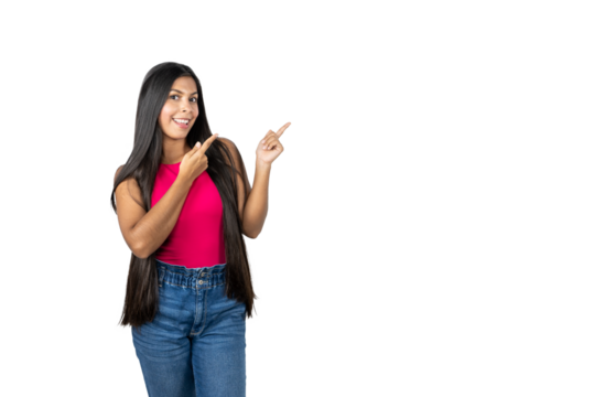 Smiling Mexican Woman with Long Hair Pointing to the Right on a White Background. Wearing a Pink Shirt and Blue Jeans - Powered by Adobe