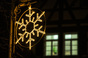 Weihnachtsbeleuchtung Schneeflocke vor erleuchtetem Fenster