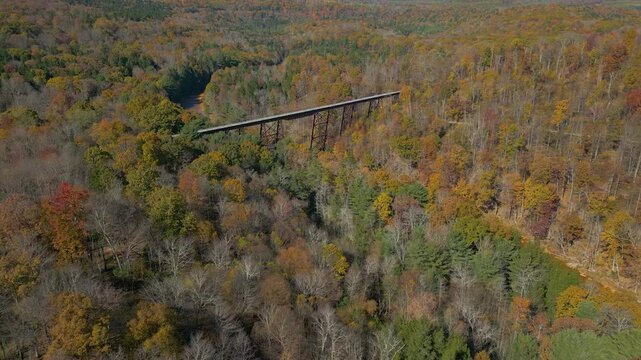 Aerial view of historic railroad bridge crossing a river valley, drone 4K