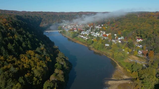 Aerial view of a small town on the mountainside with beautiful Fall foliage and fog, drone 4K