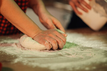 Chef kneading dough on floured wooden table in restaurant kitchen