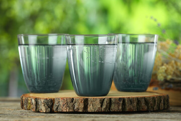 Soda water in glasses on wooden table outdoors