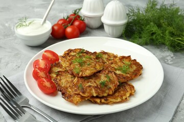 Delicious potato pancakes with fresh tomatoes served on grey table